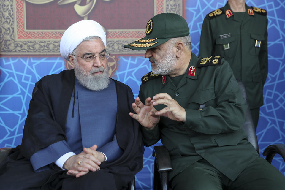 In this photo released by the official website of the office of the Iranian Presidency, President Hassan Rouhani, left, listens to chief of the Revolutionary Guard Gen. Hossein Salami at a military parade marking 39th anniversary of outset of Iran-Iraq war, in front of the shrine of the late revolutionary founder Ayatollah Khomeini, just outside Tehran, Iran, Sunday, Sept. 22, 2019. Rouhani said Sunday his country should lead regional security in the strategic Persian Gulf and warned against the presence of foreign forces, as the country's nuclear deal with world powers collapses and the U.S. deployed more troops to boost security for its Arab allies. (Iranian Presidency Office via AP)