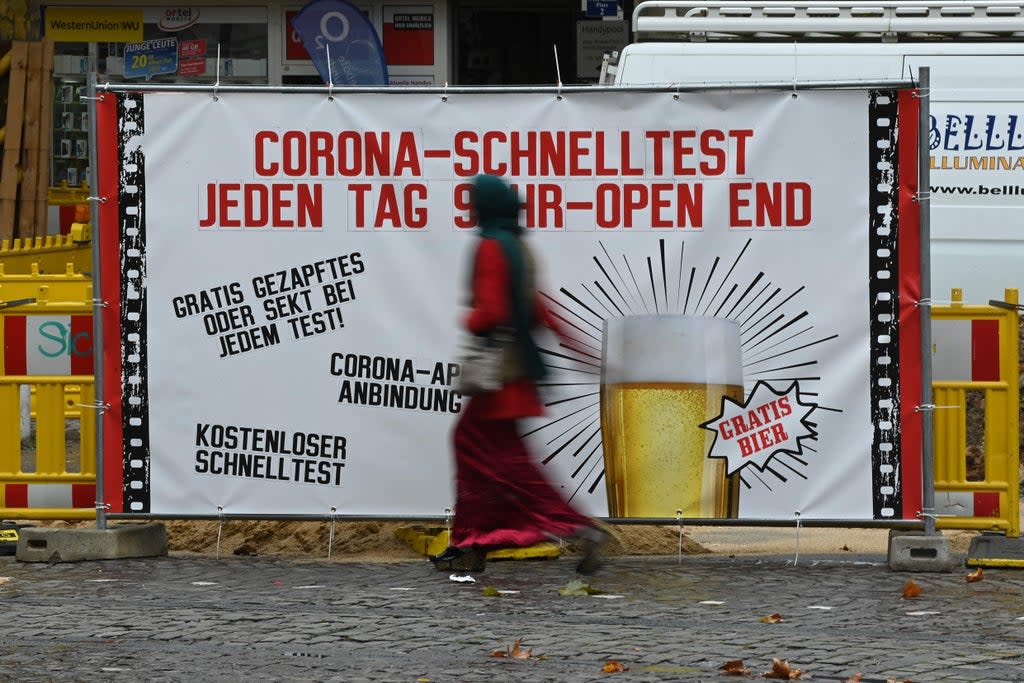 A woman walks past a placard for a coronavirus testing station in Dortmund on Thursday  (AFP via Getty Images)