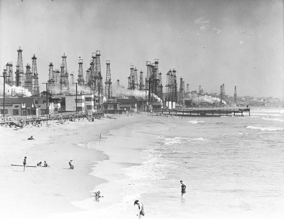 In this undated historical image provided by the University of Southern California library, people enjoy the beach in front of an oil field in Playa del Rey, Calif. There are 3.2 million abandoned oil and gas wells in the U.S., according to the Environmental Protection Agency. About a third were plugged with cement, which is considered the proper way to prevent harmful chemical leaks. But most, about 2.1 million by the EPA's count, haven't been plugged at all. (USC via AP)