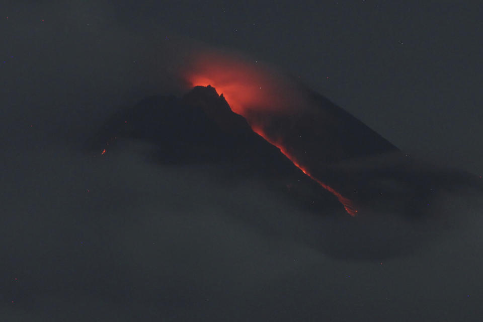 Lava flows down from the crater of Mount Merapi seen from Pakembinangun village in Sleman, Central Java, Thursday, March 10, 2022. Indonesia's Mount Merapi volcano spewed avalanches of hot clouds in eruptions overnight Thursday that forced about 250 residents to flee to temporary shelters. No casualties were reported. (AP Photo/Ranto Kresek)