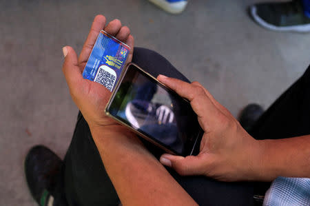 FILE PHOTO: An identification card is checked at a "Red Point," an area set up by President Nicolas Maduro's party to verify that people cast their votes, during the presidential election in Caracas, Venezuela, May 20, 2018. REUTERS/Marco Bello/File Photo