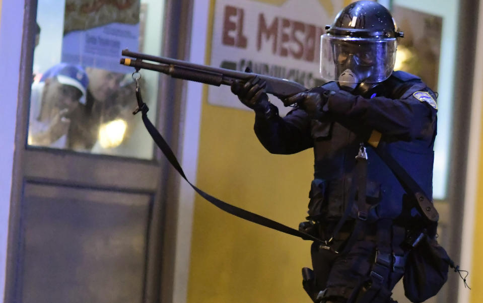 A member of the riot control units patrol the street while people look out the window during clashes in San Juan, Puerto Rico, Monday, July 22, 2019. Protesters are demanding Gov. Ricardo Rossello step down following the leak of an offensive, obscenity-laden online chat between him and his advisers that triggered the crisis. (AP Photo / Carlos Giusti)