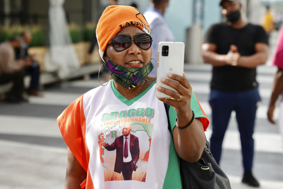 A supporter of former Ivory Coast President Laurent Gbagbo takes photos with her smartphone at the Brussels international airport in Brussels, Thursday, June 17, 2021. The former Ivory Coast president Laurent Gbagbo is returning home to Ivory Coast for the first time in nearly a decade, after his acquittal on war crimes charges was upheld at the International Criminal Court earlier this year. (AP Photo/Olivier Matthys)