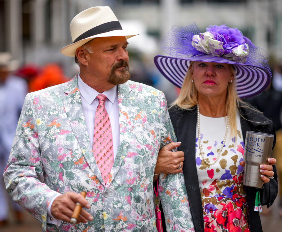 <p>A man and woman walk around Churchill Downs, perfect examples of two mainstays at the Derby: a cigar and a wide-brimmed hat. (Photo: Getty Images) </p>