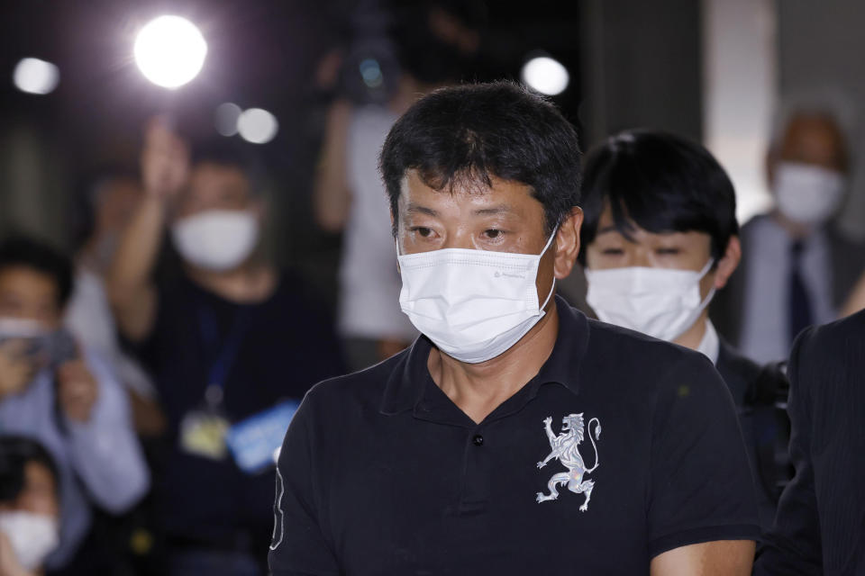 Japanese suspect Mitsuhiro Taniguchi, center, arrives at Narita International Airport in Narita, east of Tokyo, Wednesday, June 22, 2022. The suspect in a million-dollar fraud scheme using a Japanese government COVID-19 subsidy money has returned to Tokyo after being deported from Indonesia where was caught for overstaying earlier this month after being on a run for more tan a year and half. (Kyodo News via AP)