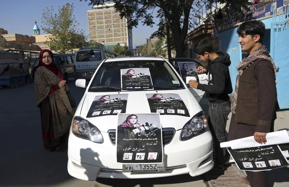 In this Sunday, Oct. 14, 2018 photo, Hameeda Danesh, a candidate for Parliament, left, stand near her car that is decorated with her campaign posters, in Kabul, Afghanistan. Danesh says Saturday’s election are key to countering the conservatism that stifles education, other opportunities for women. (AP Photo/Rahmat Gul)