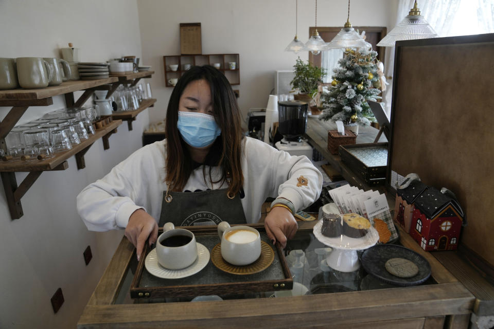 A barista prepares coffee at a cafe dubbed the "Winter Olympic Home" in Houheilong Miao, a village in Yanqing on the outskirts of Beijing, China, Wednesday, Jan. 5, 2022. The village has a view of the Olympics skiing venue in the distance. Its 20 mostly vacant traditional courtyard houses have been turned into lodgings and a cafe dubbed the "Winter Olympic Home." (AP Photo/Ng Han Guan)