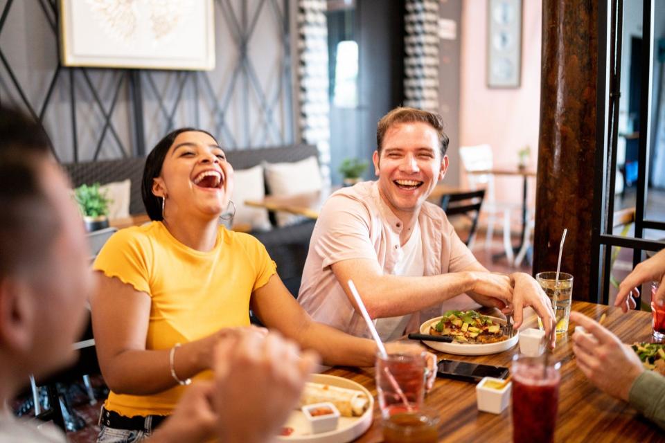 Tres personas sentadas en una mesa y riéndose. 