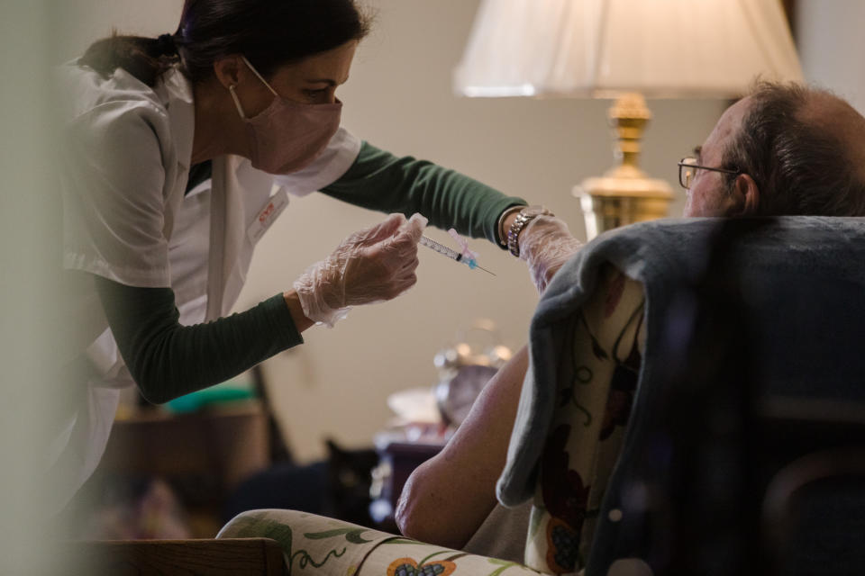 A pharmacist administers a dose of a COVID-19 vaccine