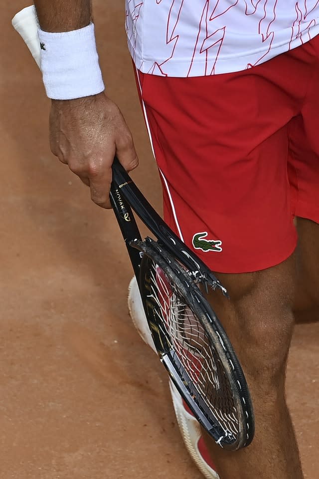 Novak Djokovic carries his broken racket