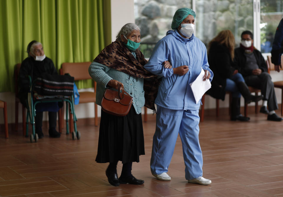 Una enfermera ayuda a una anciana a caminar para recibir su inyección de la vacuna Sinopharm COVID-19 en el hogar de ancianos San Ramón durante el inicio de la inmunización para personas mayores de 80 años en La Paz, Bolivia, el lunes 5 de abril de 2021. ( Foto AP/Juan Karita)