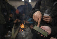 Migrants check a map depicting the Hungarian - Serbian border area while bracing against harsh winter weather inside an abandoned hangar near the Hungarian border, outside of the village of Majdan, Serbia, Tuesday, Jan. 11, 2022. Hungary's nationalist prime minister, Viktor Orban, is keen to use the threat of migrants at his country's southern border to give him an advantage in upcoming elections. But the scale of migration pressure claimed by Orban is drawn into question by statistics from neighboring Serbia and the European Union's border agency. (AP Photo/Bela Szandelszky)