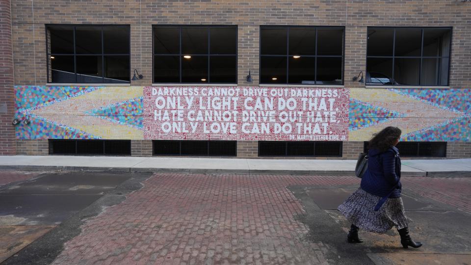 A woman walks past a mural highlighting the words of Martin Luther King Jr. on the Short North Garage.