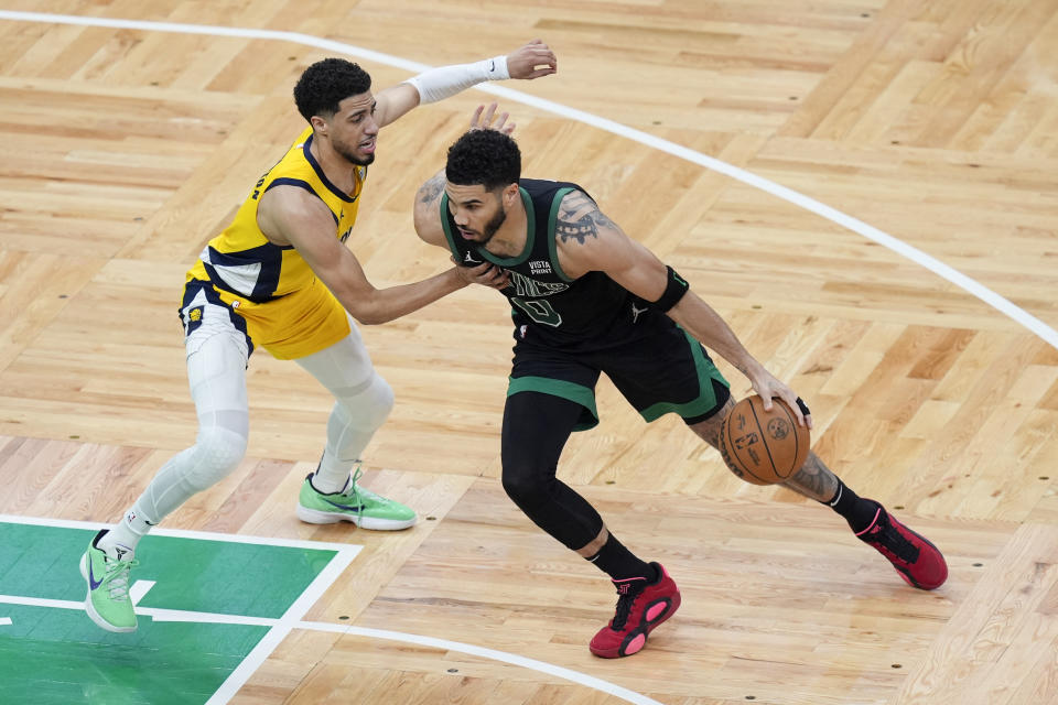 Boston Celtics forward Jayson Tatum (0) is defended by Indiana Pacers guard Tyrese Haliburton, left, during the first half of Game 2 of the NBA Eastern Conference basketball finals on Thursday, May 23, 2024, in Boston.  (AP Photo/Michael Dwyer)