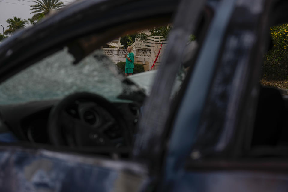 A woman stands by a car damaged by a rocket fired Wednesday night from the Gaza Strip by Palestinian militants in Ashkelon, Israel, Thursday, May 11, 2023. (AP Photo/Ariel Schalit)