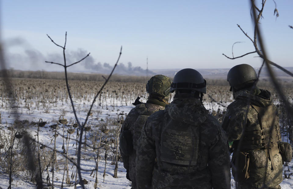 Ukrainian soldiers watch as smoke billows during fighting between Ukrainian and Russian forces in Soledar, Donetsk region, Ukraine, Wednesday, Jan. 11, 2023. (AP Photo/Libkos)