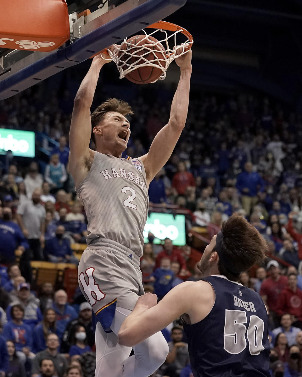 Kansas' Christian Braun (2) gets past Nevada's Will Baker (50) to dunk the ball during the first half of an NCAA college basketball game Wednesday, Dec. 29, 2021, in Lawrence, Kan. (AP Photo/Charlie Riedel)