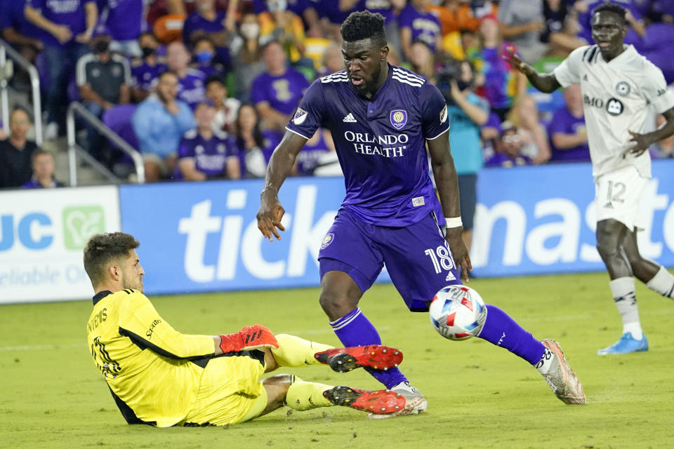 CF Montreal goalkeeper James Pantemis, left, blocks a shot on goal by during the second half of an MLS soccer match, Wednesday, Oct. 20, 2021, in Orlando, Fla. (AP Photo/John Raoux)