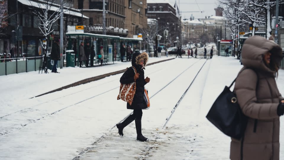 People cross a snow covered railway in Helsinki, Finland, on April 23, 2024, as an unusual weather system brought trams in the city to a halt. - Alessandro Rampazzo/Anadolu Agency/Getty Images
