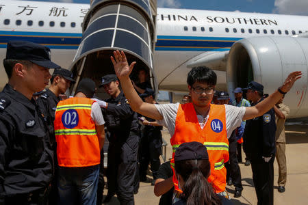 Chinese nationals (in orange vests) who were arrested over a suspected internet scam, are escorted by Chinese police officers before they were deported at Phnom Penh International Airport, in Phnom Penh, Cambodia, October 12, 2017. REUTERS/Samrang Pring