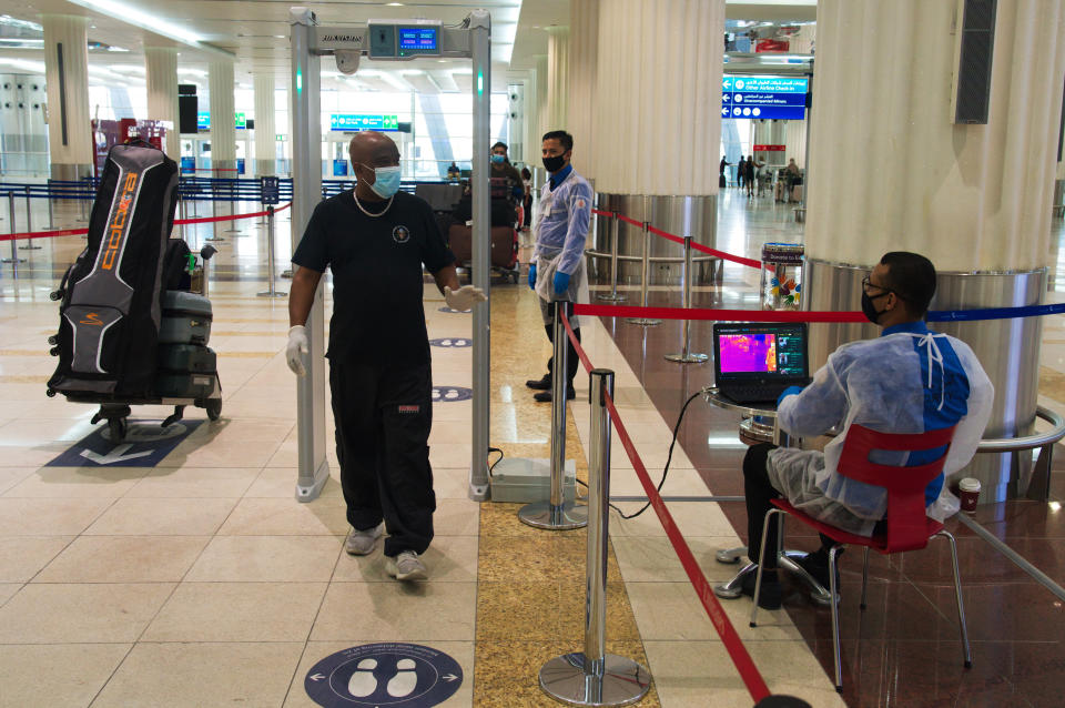 FILE - In this June 10, 2020 file photo, passenger wearing a mask due to the coronavirus pandemic passes through a temperature screening at Dubai International Airport's Terminal 3 in Dubai, United Arab Emirates. Hundreds of thousands of foreign residents of the UAE are struggling to return to the country after a lockdown over the coronavirus. They left behind jobs, families, homes and other responsibilities of which they always planned to return. But some tell The Associated Press they still face challenges in trying to come back. (AP Photo/Jon Gambrell, File)