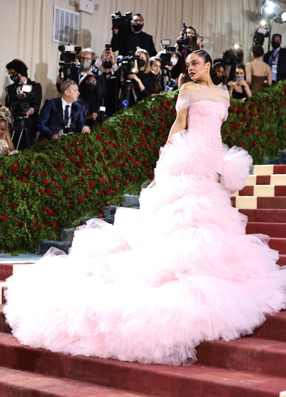 Tessa standing on the stairs and wearing a gown with long, flowing, tulle train