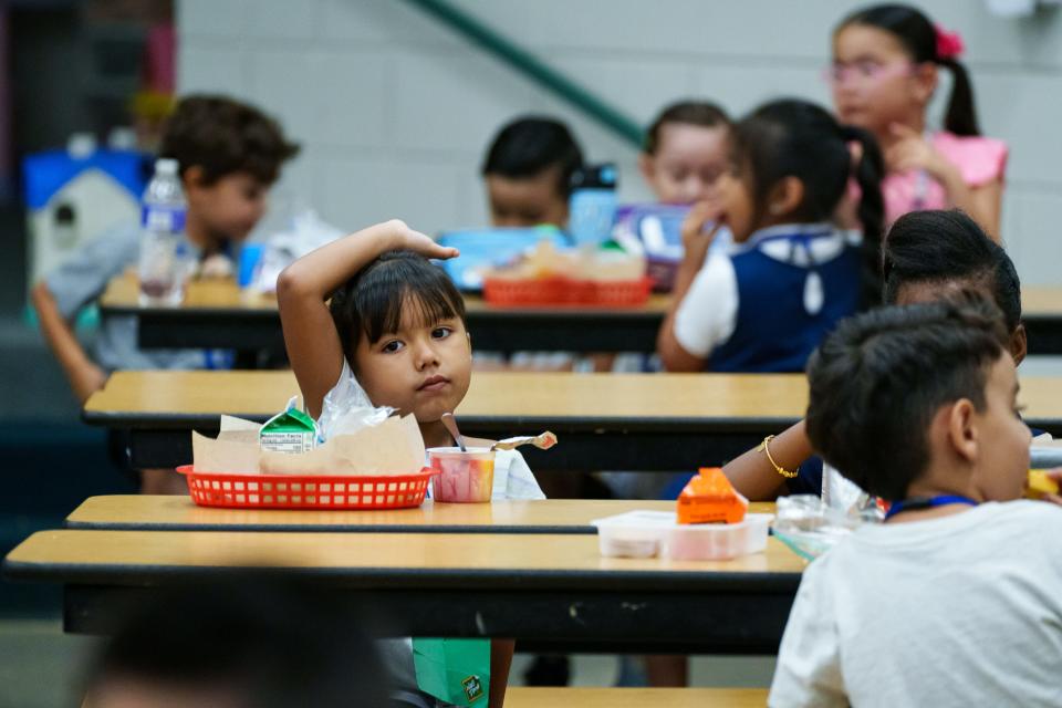 Kindergartener Arianna Hernandez raises her hand at the lunch table at Alhambra Traditional School on Aug. 28, 2023, in Phoenix.