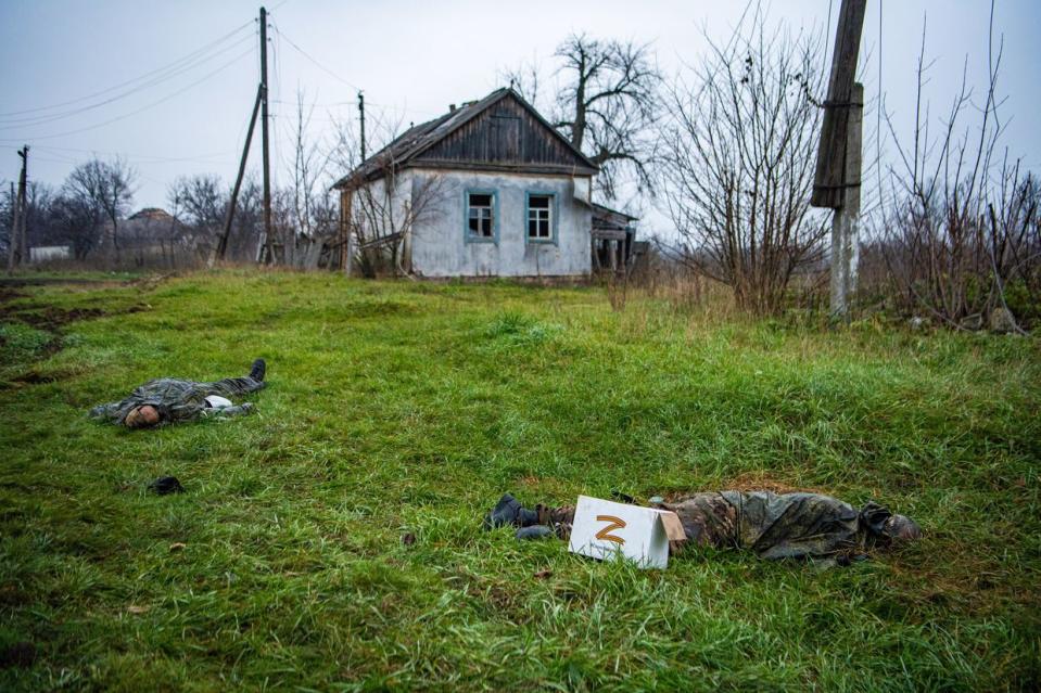 The dead bodies of two Russian soldiers lie on the grass in front of a house in the liberated village of Makiivka in Ukraine's eastern Luhansk Oblast. A cardboard box with the letter "Z," a symbol of the Russian army, is placed in front of one of the bodies. Heavy fighting took place around the village just days after being liberated by Ukrainian forces. (Laurel Chor/SOPA Images/LightRocket via Getty Images)