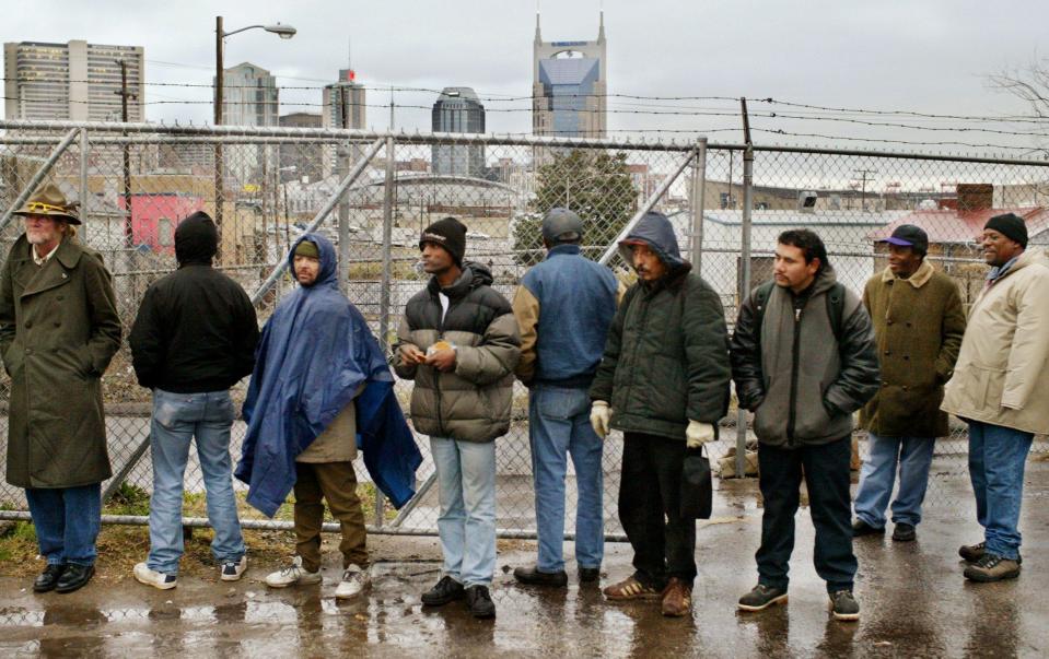 Homeless men wait in line in an alley off Eighth Avenue South for a ride to Rooms in the Inn on Dec. 10, 2003, a program sponsored by area that supplies hot meals and warm beds