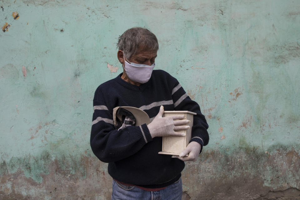 Elder Sanchez caresses the marble urn that contains the cremated ashes of his 76-year-old father who is suspected to have died from the new coronavirus, in the El Callao district of Lima, Peru, Tuesday, May 5, 2020. Peruvian officials call the virus the most devastating pandemic to hit the country since 1492, when Europeans began bringing diseases like smallpox and measles to the Americas. (AP Photo/Rodrigo Abd)