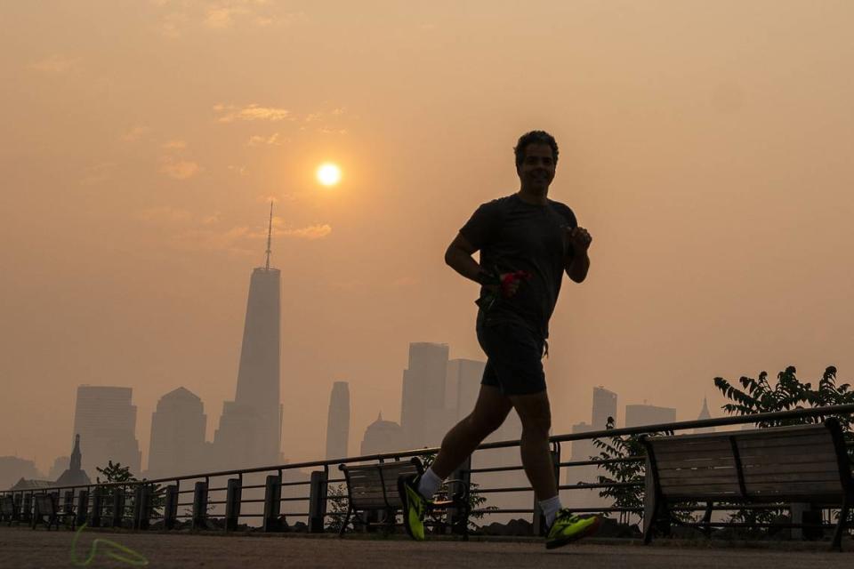 El One World Trade Center y el horizonte de Nueva York se ven al fondo mientras un hombre se ejercita en el Liberty State Park y el humo de los incendios forestales de Canadá cubre Manhattan, el jueves 8 de junio de 2023, en Nueva Jersey. Eduardo Munoz Alvarez/Getty Images via TNS