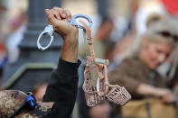 In this photo taken on Saturday, Sept. 19, 2020 a man waves handcuffs attached to muzzles during a protest against the COVID-19 pandemic restrictions in Bucharest, Romania. Across the Balkans and the rest of the nations in the southeastern corner of Europe, a vaccination campaign against the coronavirus is overshadowed by heated political debates or conspiracy theories that threaten to thwart the process. In countries like the Czech Republic, Serbia, Bosnia, Romania and Bulgaria, skeptics have ranged from former presidents to top athletes and doctors. Nations that once routinely went through mass inoculations under Communist leaders are deeply split over whether to take the vaccines at all. (AP Photo/Vadim Ghirda)