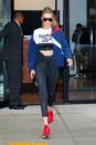 <p>In a Reebok crop top, blue windbreaker, a quilted sweater tied around the waist, detailed workout leggings, red trainers and sunglasses while out in New York. </p>