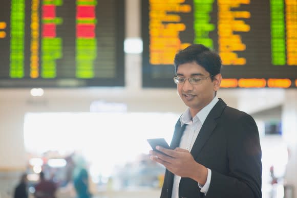 A young man checks his phone at the train station.