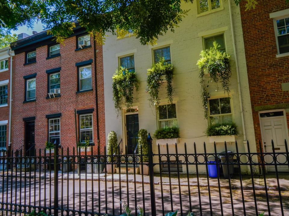 A row of residential mews on a street shaded by trees.