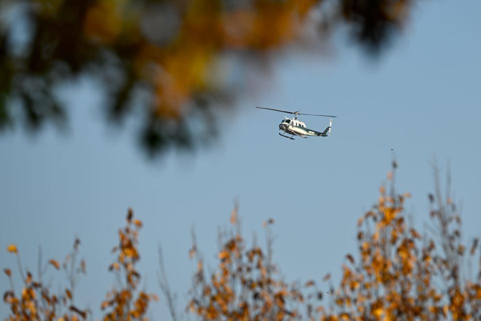 A helicopter lands behind Lewiston High School as part of the aerial searches after the mass shooting.