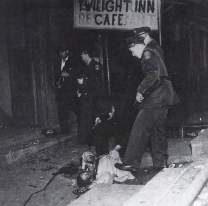 John Blackwell lies in the street after being beaten and dragged down the steps of the Loge Hall during the Tennessee Highway Patrol's early morning raid of Columbia's Black business district, the Bottom, on Feb. 26, 1946. Policeman Frank T. Collins and Constable Homer Copeland are seen passing in the background.