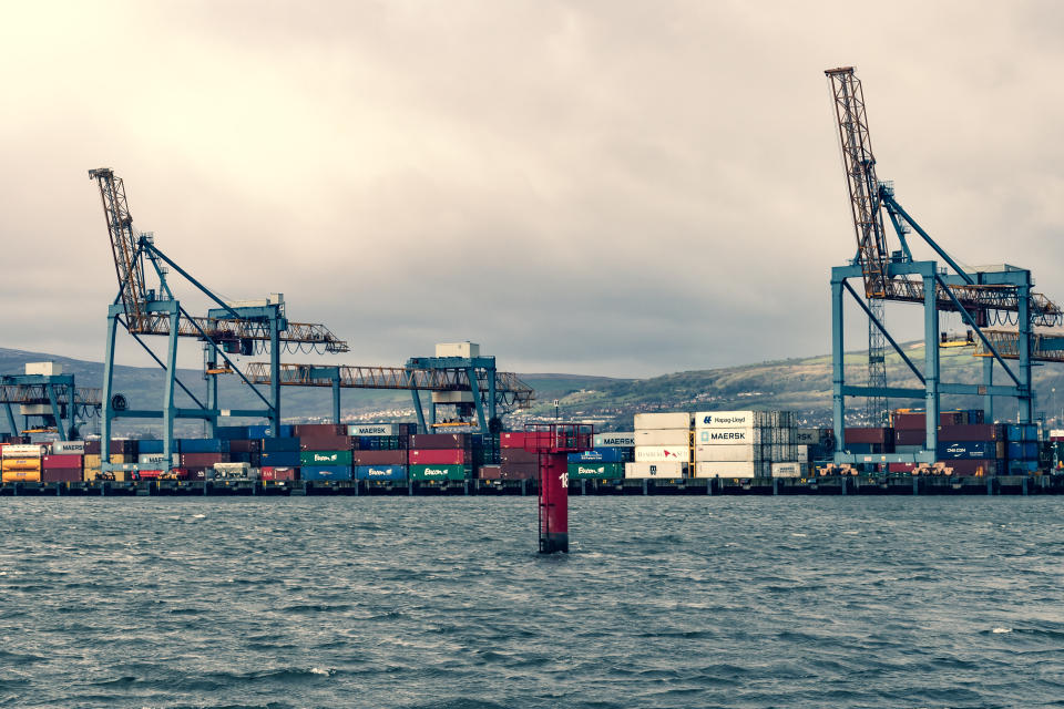 Belfast, United Kingdom: March 10, 2019:  Shipping containers stacked high at the container dock of Belfast Harbour, Northern Ireland.  As the proposed date for the UK's departure from the EU approaches (Brexit), manufacturers and retailers have stock piled goods at the port in shipping containers just in case the terms of Brexit disrupt supplies.  Cross-processed.