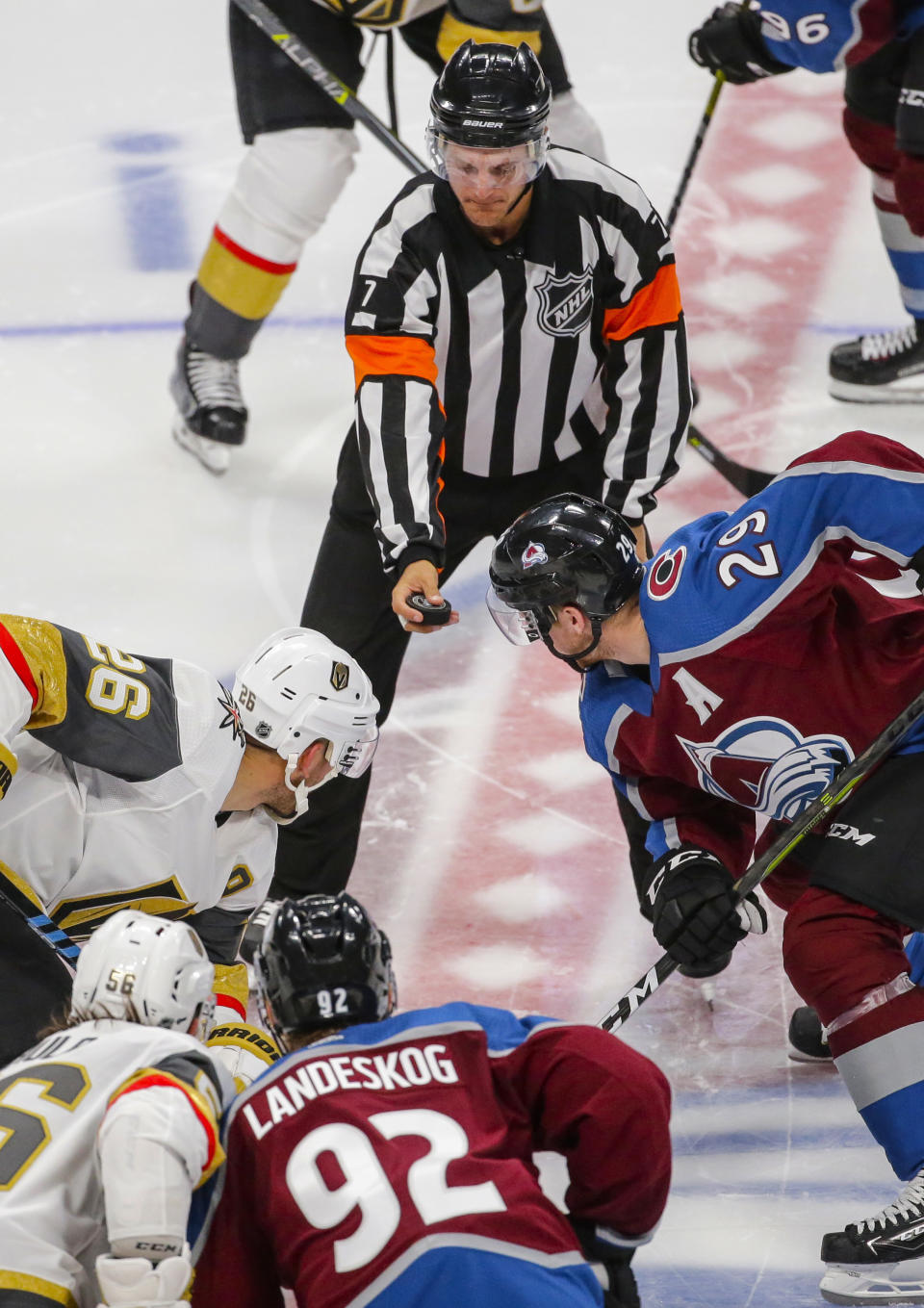 FILE - Referee Garrett Rank (7) drops the puck for Vegas Golden Knights center Paul Stastny (26) and Colorado Avalanche center Nathan MacKinnon (29) during the third period of a preseason NHL hockey game Tuesday, Sept. 18, 2018, in Denver. Growing up in a small town in southern Ontario, Rank played hockey in the winter and golfed in the summer. As an adult, he's able to do the same thing — just replace playing with refereeing. (AP Photo/Jack Dempsey, File)