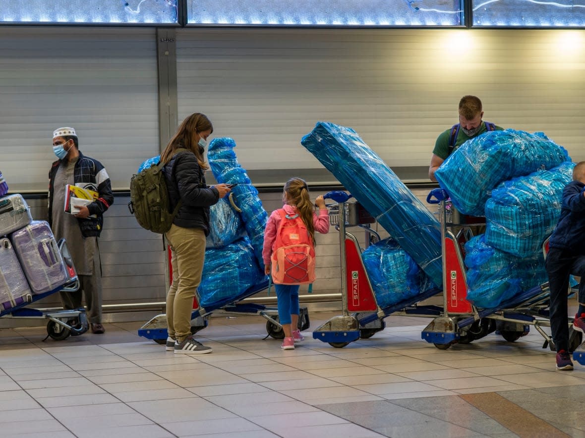 People line up to get on an overseas flight at OR Tambo's airport in Johannesburg, South Africa on Friday Nov. 26, 2021. A slew of nations moved to stop air travel from southern Africa on Friday in reaction to news of a new, potentially more transmissible COVID-19 variant that has been detected in South Africa. (Jerome Delay/AP Photo - image credit)