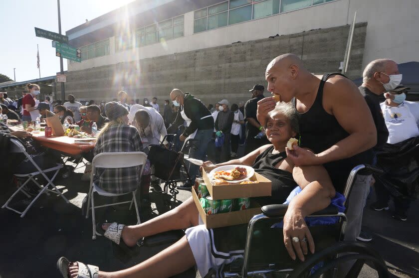 Bobby Diaz and his mother, Gina, partake in a free Thanksgiving meal provided by the Union Rescue Mission as the Los Angeles Skid Row district annual feast hosts thousands of homeless and others in need in downtown Los Angeles, Thursday, Nov. 24, 2022. (AP Photo/Damian Dovarganes)