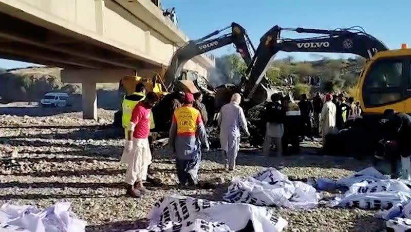 People work at the site of a bus crash in Lasbela District