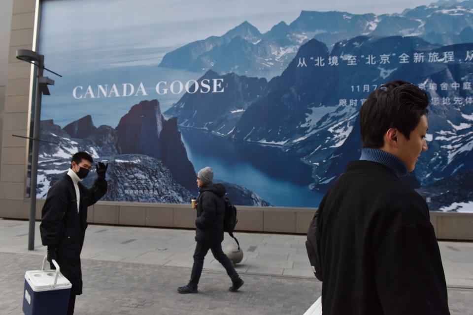 People walk past a Canada Goose billboard in Beijing on December 15, 2018. - Canada Goose, the Canadian manufacturer of high-end parkas, postponed the opening of its store in Beijing on December 15, a decision that comes in the midst of a diplomatic crisis over Canada's arrest of the chief financial officer of Chinese telecom giant Huawei. (Photo by GREG BAKER / AFP)        (Photo credit should read GREG BAKER/AFP via Getty Images)