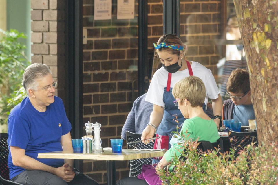 SYDNEY, AUSTRALIA - JANUARY 03: A waitress is seen delivering cutlery at a cafe in Mosman on January 03, 2021 in Sydney, Australia. Face masks are now compulsory in certain indoor settings across NSW as the state continues to record new COVID-19 cases in the community. As of midnight, face masks are mandatory on public transport, in retail shops and supermarkets, indoor entertainment including cinemas and theaters, places of worship and hair and beauty premises. Face masks are also mandatory for all staff in hospitality venues and casinos and for patrons using gaming services. Stay at home lockdown orders for residents in the southern zone of the Northern Beaches have now been lifted, with the area now subject to the same restrictions as Greater Sydney, while the northern Northern Beaches area remains under lockdown until 9 January.  (Photo by Jenny Evans/Getty Images)