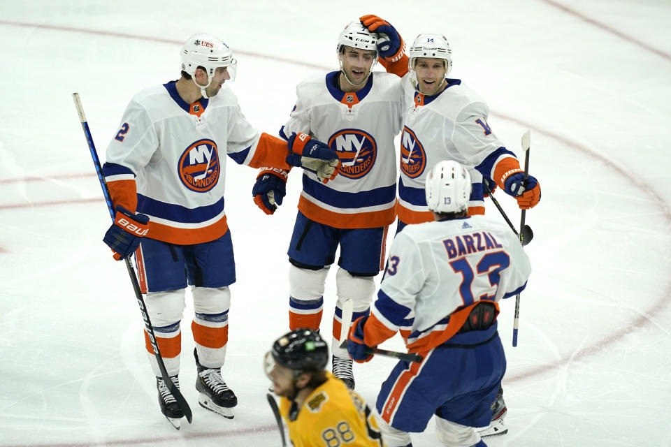 New York Islanders center Travis Zajac (14) celebrates his goal with teammates as Boston Bruins right wing David Pastrnak (88) skates by in the second period of an NHL hockey game, Thursday, April 15, 2021, in Boston. (AP Photo/Elise Amendola)