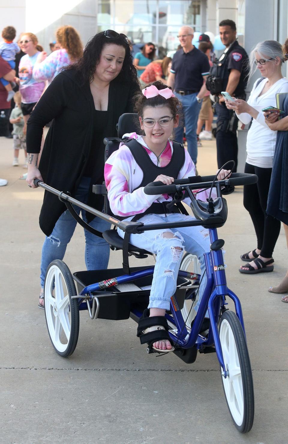 Bre McClure, left, helps her daughter Miah, 15, with her new adaptive tricycle that was presented this week to the Hoover High student at Cain Toyota-BMW in Jackson Township.