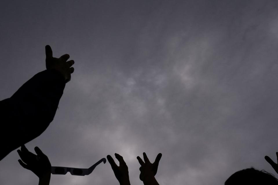 People hold their hands up to the sky, hoping the clouds will part during cloudy conditions to see a total solar eclipse at Dunkirk Lighthouse & Veterans Park Museum in Dunkirk, N.Y.<span class="copyright">Elizabeth Frantz—Reuters</span>