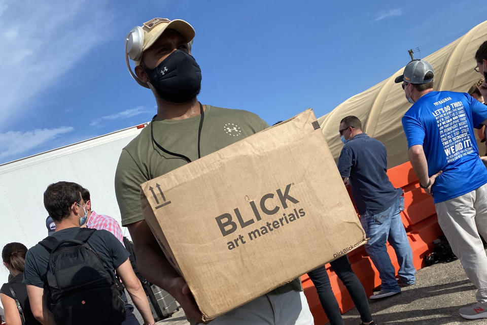 Image: A member of the Guantanamo Bay detention facility staff accepts a box of donated art materials for guards and detainees. (U.S. Office of Military Commissions)