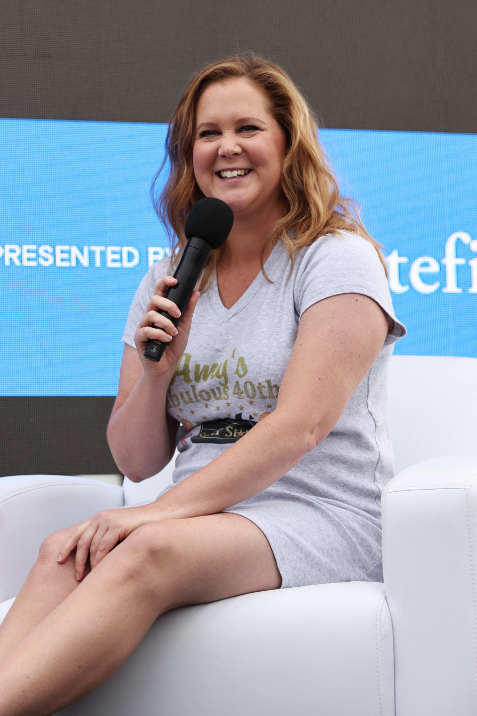 Amy Schumer smiling with a mic in her hand