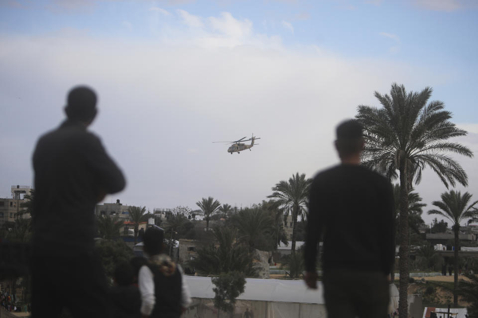 Palestinians watch an Israeli helicopter fly over Khan Younis, Gaza Strip, Thursday, Feb. 15, 2024. (AP Photo/Mohammed Dahman)